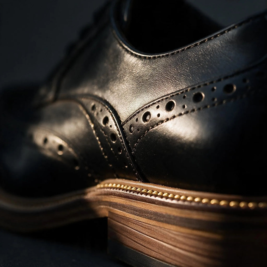 Close-up of the black leather heel and stacked sole with contrast stitching on a brogue derby shoe