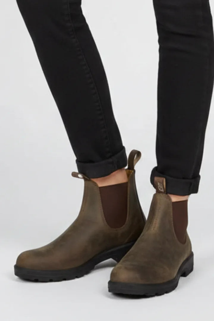 Close-up of black skinny trousers cuffed above brown leather Chelsea boots with pull tab detail