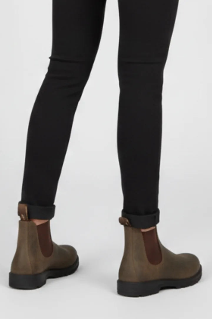 Rear view showing pull tab loops and stitching on brown Chelsea boots against black cuffed trousers