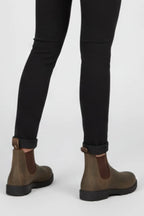 Rear view showing pull tab loops and stitching on brown Chelsea boots against black cuffed trousers