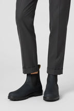 Front view of black Chelsea boots with pull tab and elastic gusset styled with cropped grey trousers
