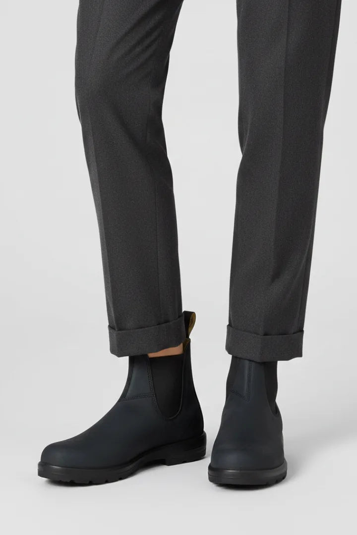 Front view of black Chelsea boots with pull tab and elastic gusset styled with cropped grey trousers