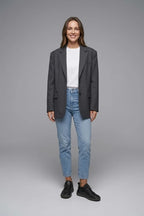 Woman in denim jeans and a grey blazer wearing black leather trainers with white t-shirt for a smart-casual look