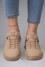 Close-up front view of feet wearing beige leather trainers with SPORT branded tongue and stitched panel detailing