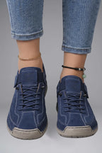 Close-up front view of feet wearing dark blue leather trainers with lace-up front and elastic side strap