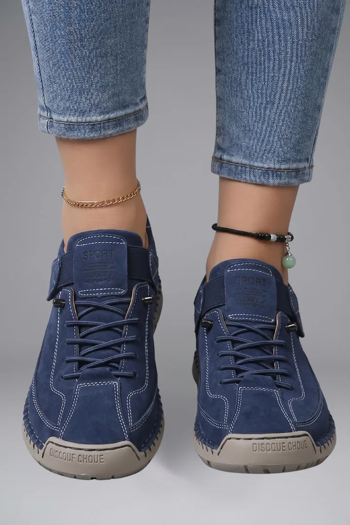Close-up front view of feet wearing dark blue leather trainers with lace-up front and elastic side strap