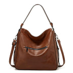 Front view of the brown hobo bag with layered zip pockets, tassel detail and long adjustable strap