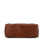 Side profile of the brown hobo bag showing its rounded base, tall handle and side zip pull