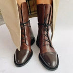 Front view of brown leather lace-up boots with contrast black laces and cap toe detail