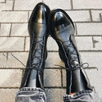 Overhead view of black leather lace-up boots seen from above, showing the pointed cap toe
