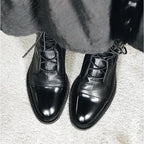 Top-down view of black leather lace-up boots with cross laces, worn with cropped jeans