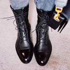 Close-up top view of black leather lace-up boots showing the ribbed sole and stitched welt