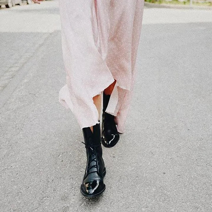 Front view of black leather lace-up boots worn with a pale pink midi dress, holding a bouquet