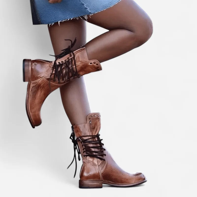 Tan brown leather lace-up boots styled with a denim skirt, showing the stud trim on the ankle cuff