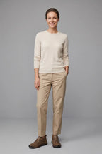 Woman in a beige jumper and beige trousers wearing brown leather lace-up comfort trainers