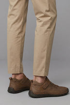 Rear angled view of brown leather trainers showing whipstitched sole and heel pull tab