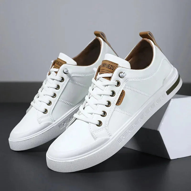 Angled view of white leather trainers with tan heel tab and lace-up front, resting against a white box