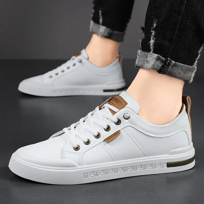 White leather trainers worn with rolled-up black jeans, shown from a low front angle