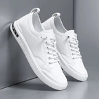 Front angled view of white leather trainers leaning against a wall, showing rounded toe and laces