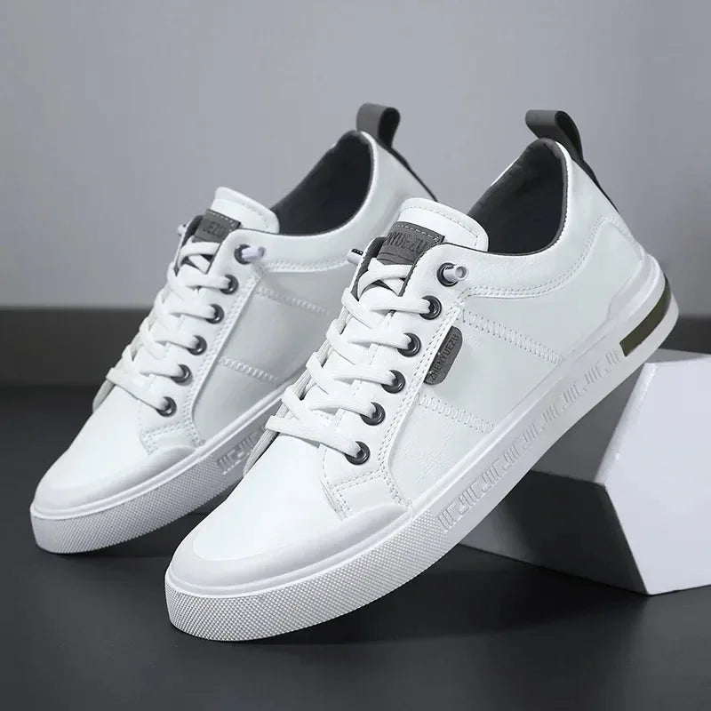 Pair of white trainers with grey heel tab and black eyelets, angled beside a geometric white box