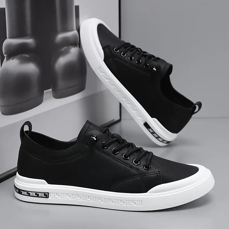 Pair of black leather trainers, one upside down showing the patterned white sole and heel pull tab
