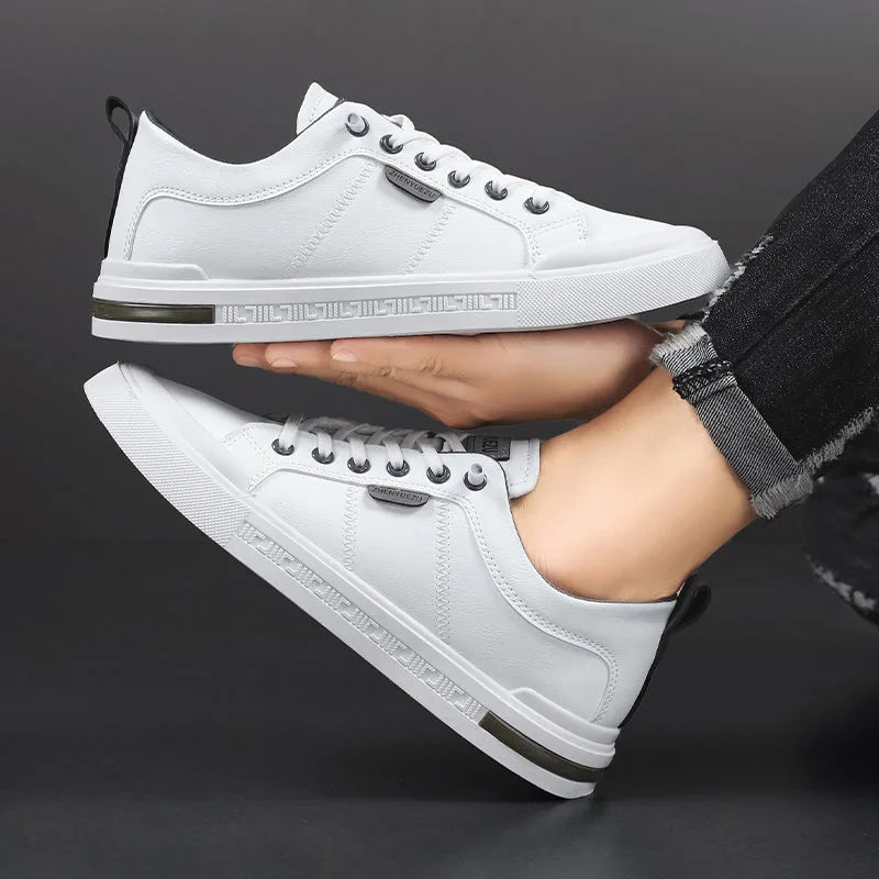 Close-up of white trainer held in hand against a rolled denim trouser leg, showing sole tread detail
