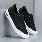 Close-up side angle of black leather trainers leaning together, highlighting stitching and sole trim