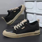 Side profile of black trainer showing cream heel tab, tan midsole trim and embossed sidewall pattern