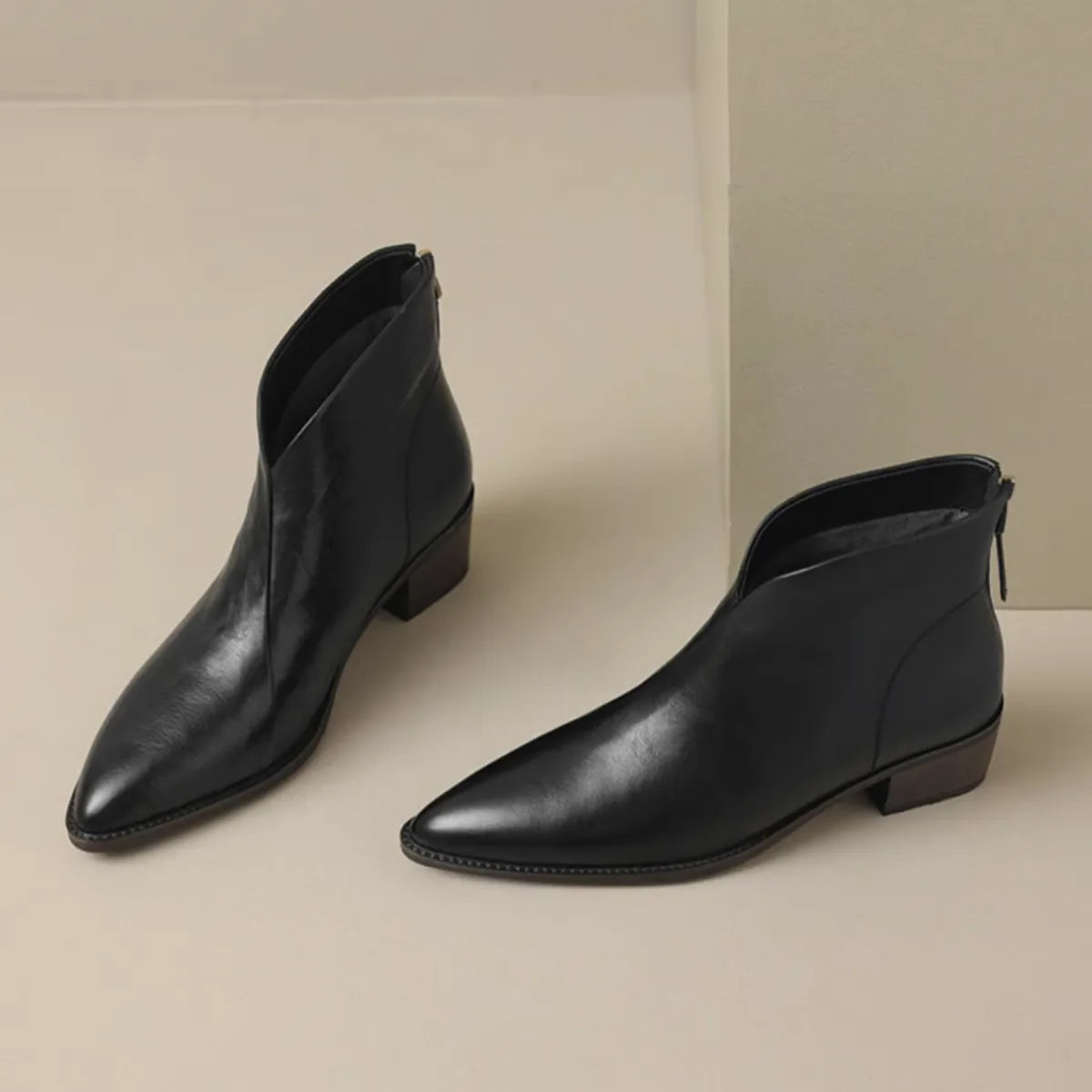 Side profile of black leather ankle boot with pointed toe and low stacked wooden heel