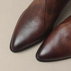 Close-up of brown leather ankle boots showing gold-tone back zip and stacked heel