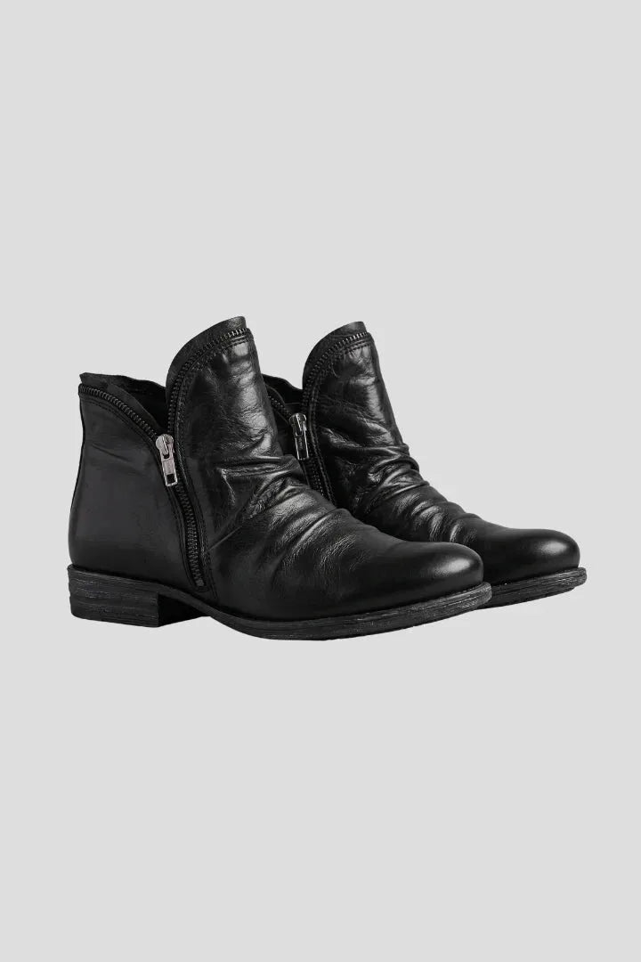 Pair of black leather ankle boots with ruched shaft and side zip, shown at an angle on a grey background