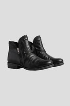 Pair of black leather ankle boots with ruched shaft and side zip, shown at an angle on a grey background