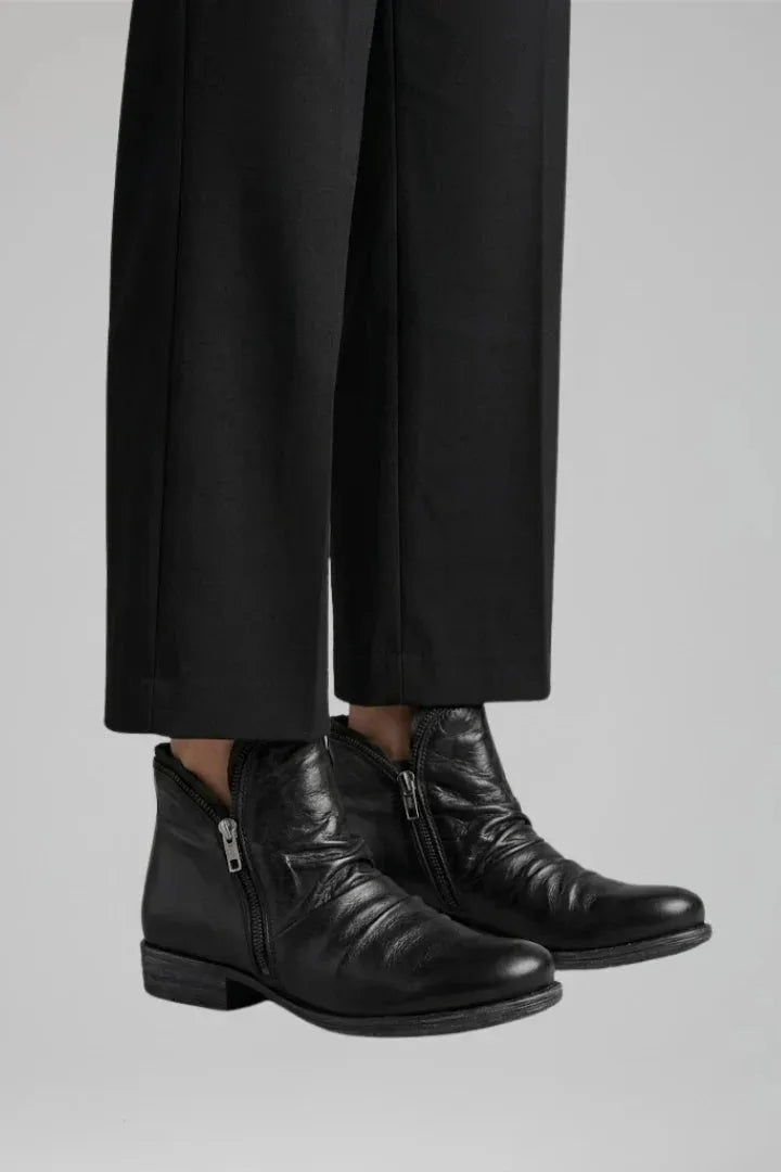 Side view of black leather ankle boots with visible zip pull and slouched leather texture
