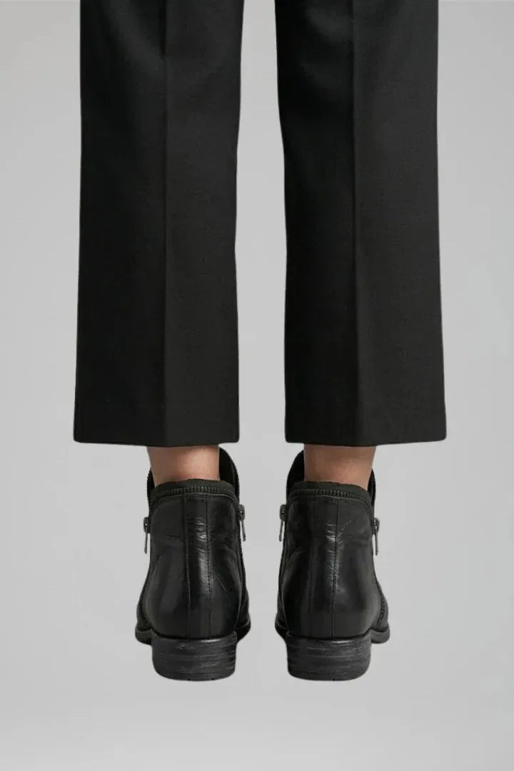 Back view showing the zip closures and stitched heel seam of the black leather ankle boots