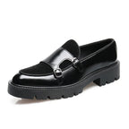 Angled shot of glossy black leather loafer with suede insert, twin buckles and chunky ridged sole on white background