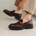 Model wearing burgundy leather double monk loafers with cropped tan trousers, showing the low chunky heel