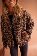 Woman smiling in an oversized leopard print jacket with silver snap buttons, worn open over a black top