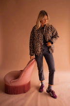 Full length view of the leopard print jacket styled with grey jeans and burgundy trainers