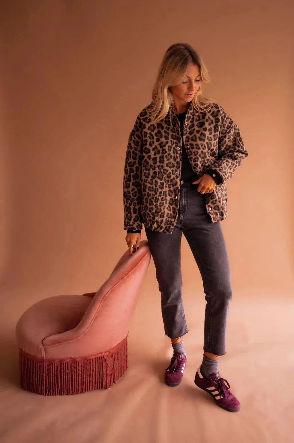 Full length view of the leopard print jacket styled with grey jeans and burgundy trainers