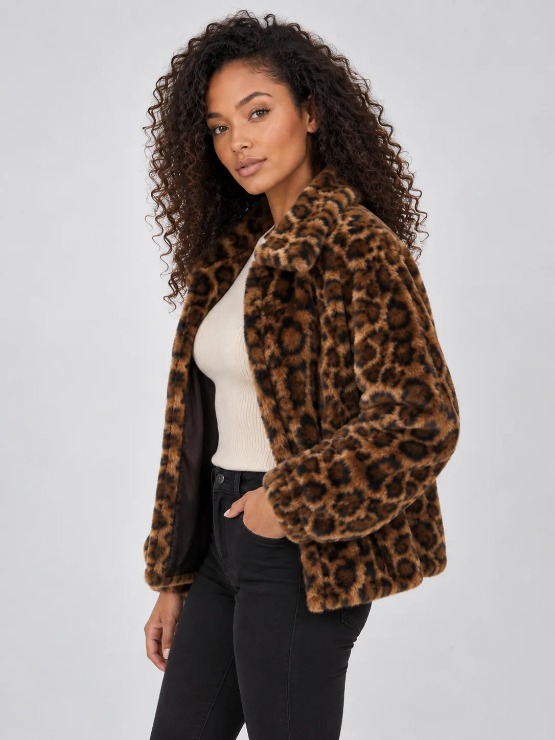 Side angle of the leopard print faux fur jacket worn open over a cream jumper, showing the relaxed hip-length fit