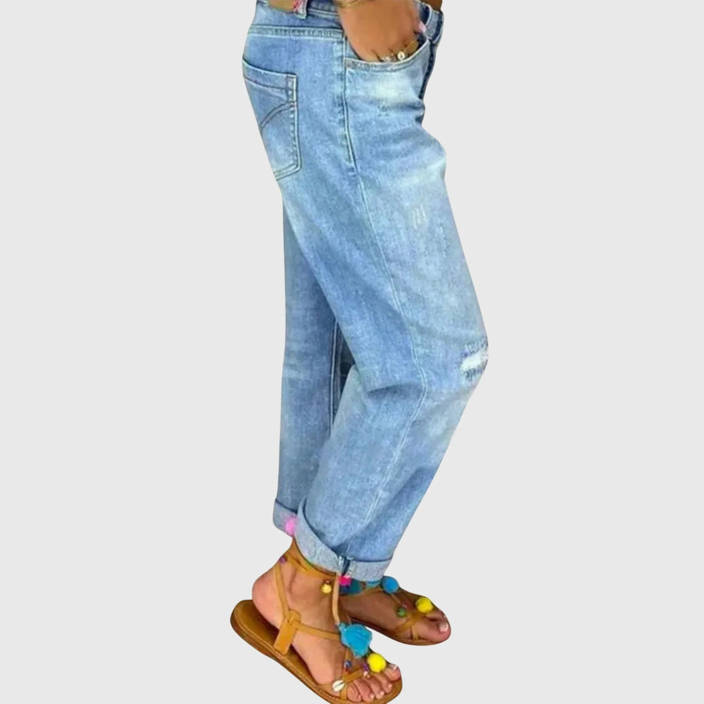 Side profile of relaxed-fit denim jeans showing back pocket detail and rolled-up ankle cuffs
