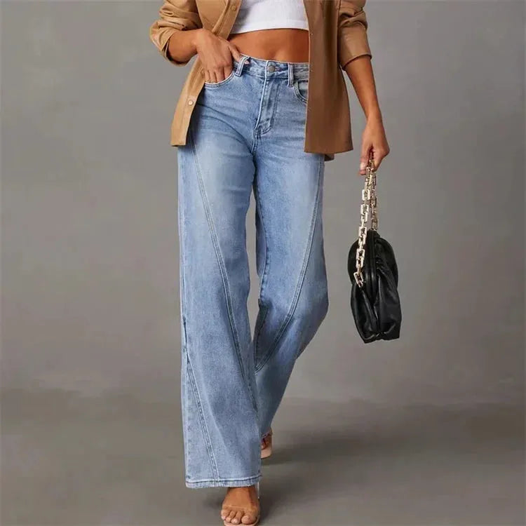 Model walking in the wide-leg jeans holding a black chain-strap handbag, side front view