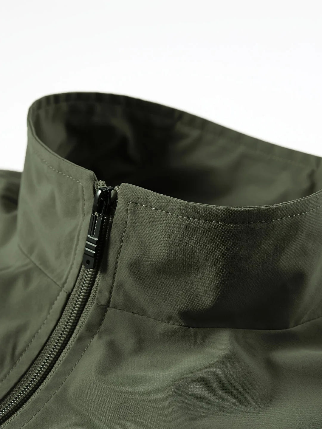 Close-up of olive green gilet collar with zip pull and reinforced stitching at the neckline