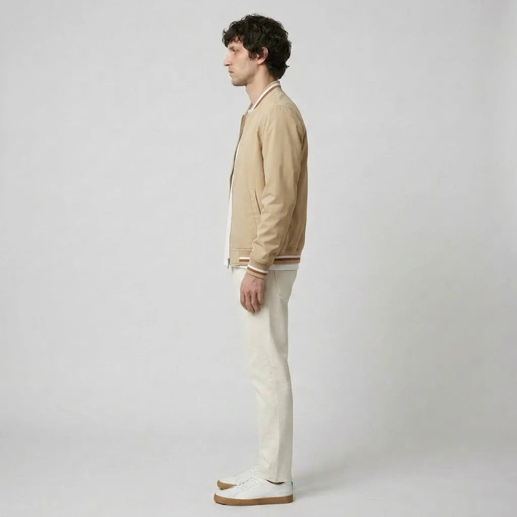 Side profile of a man wearing the beige bomber jacket with light trousers and white trainers