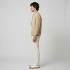 Side profile of a man wearing the beige bomber jacket with light trousers and white trainers