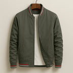 Olive green bomber jacket on a hanger with red, white and grey striped ribbing at collar and cuffs