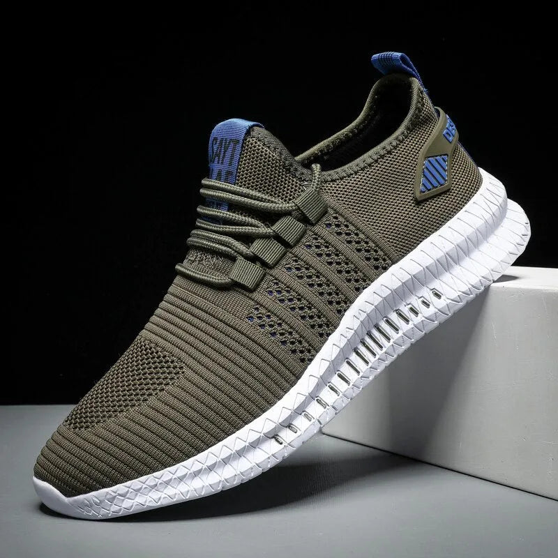 Side view of military green knit trainer with blue laces and heel tab, white chunky sole on grey background