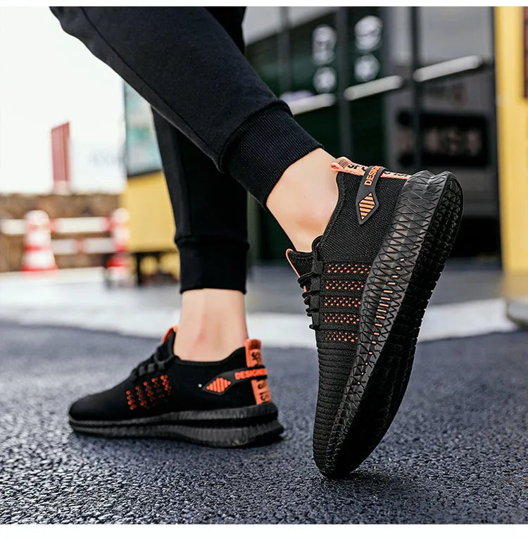 On-foot close-up of black and orange knit trainer lifted mid-step, showing textured black outsole