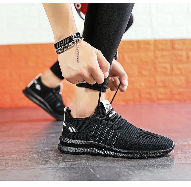 Close-up of hands lacing a black and white knit trainer with striped heel tab detail