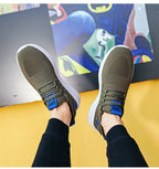 Top-down view of a pair of military green knit trainers with blue laces and white soles, feet raised
